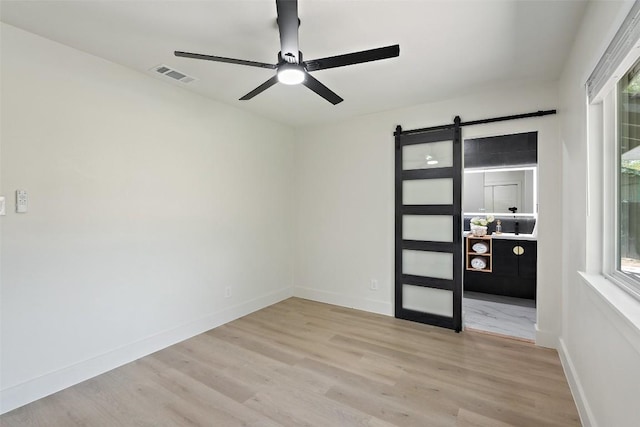 5603 Darlington Ln, Austin, TX 78723 - spare room with a ceiling fan, a barn door, wood finished floors, and healthy amount of natural light