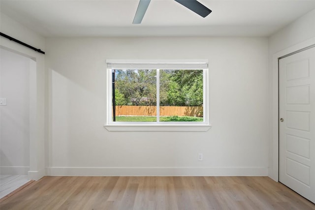 5603 Darlington Ln, Austin, TX 78723 - unfurnished bedroom with light wood-style floors, a barn door, and a ceiling fan