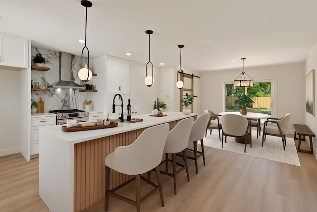 5603 Darlington Ln, Austin, TX 78723 - kitchen with wall chimney range hood, stainless steel stove, light wood finished floors, light countertops, and white cabinets
