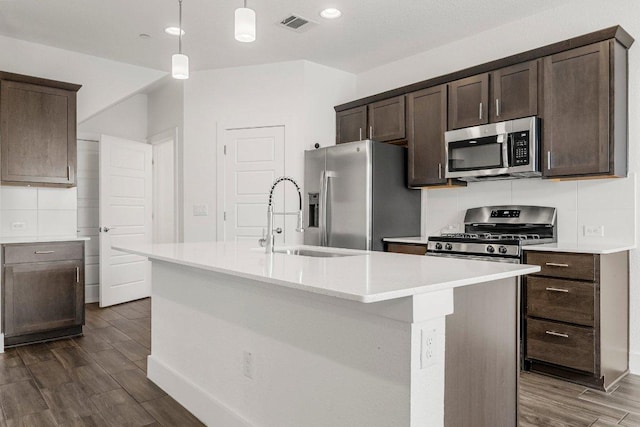 12315 Maypole Bnd Unit 1002, Austin, TX 78717 - kitchen with appliances with stainless steel finishes, dark brown cabinetry, dark wood-style flooring, an island with sink, and recessed lighting