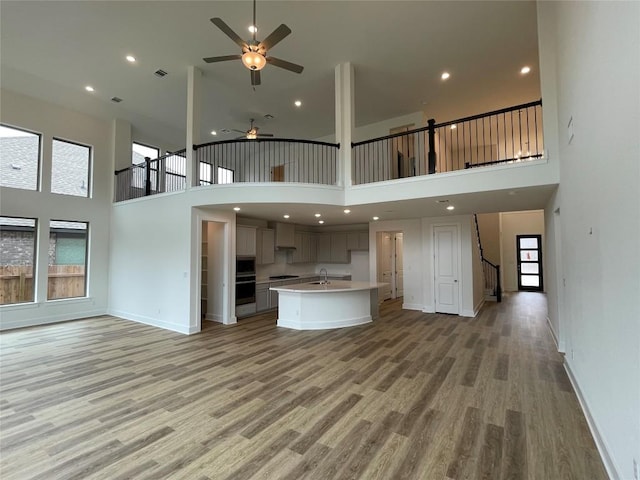 221 Camille St, Leander, TX 78641 - unfurnished living room with a ceiling fan, a high ceiling, light wood-style flooring, stairway, and recessed lighting