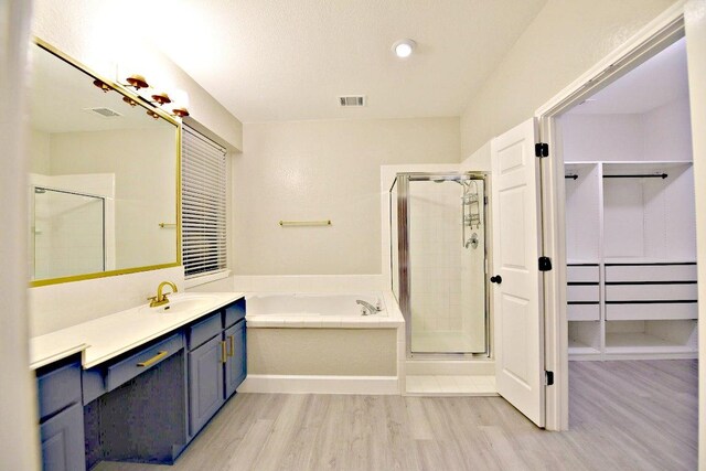 1933 Chasewood Dr, Austin, TX 78727 - bathroom featuring wood finished floors, a garden tub, a shower stall, vanity, and a walk in closet