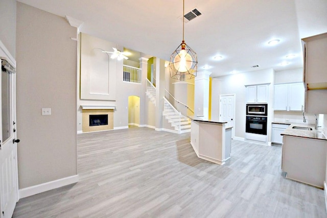 1933 Chasewood Dr, Austin, TX 78727 - kitchen with black oven, built in microwave, open floor plan, ornate columns, and a large fireplace