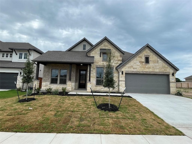 1824 Camay St, Leander, TX 78641 - view of front of home featuring driveway, stone siding, a front yard, an attached garage, and roof with shingles