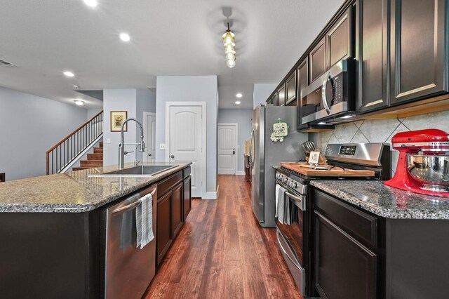 204 Parable Cv, Pflugerville, TX 78660 - kitchen with stainless steel appliances, backsplash, dark wood-type flooring, a kitchen island with sink, and dark stone countertops