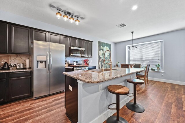 204 Parable Cv, Pflugerville, TX 78660 - kitchen with stainless steel appliances, tasteful backsplash, wood finished floors, and a kitchen breakfast bar