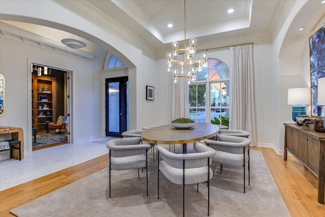 6717 Valburn Dr, Austin, TX 78731 - dining area featuring light wood-style flooring, a chandelier, arched walkways, ornamental molding, and a raised ceiling