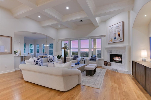 6717 Valburn Dr, Austin, TX 78731 - living room featuring arched walkways, light wood-type flooring, beam ceiling, a premium fireplace, and healthy amount of natural light