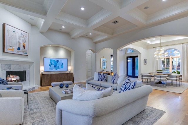 6717 Valburn Dr, Austin, TX 78731 - living room with arched walkways, beamed ceiling, a chandelier, coffered ceiling, and light wood-style floors