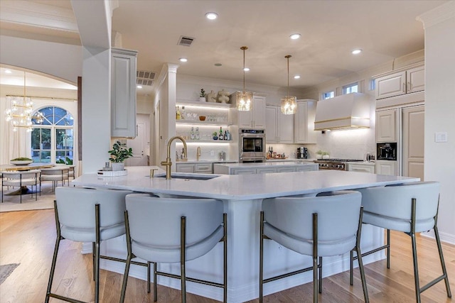 6717 Valburn Dr, Austin, TX 78731 - kitchen with premium range hood, double oven, light wood-style flooring, a kitchen bar, and recessed lighting