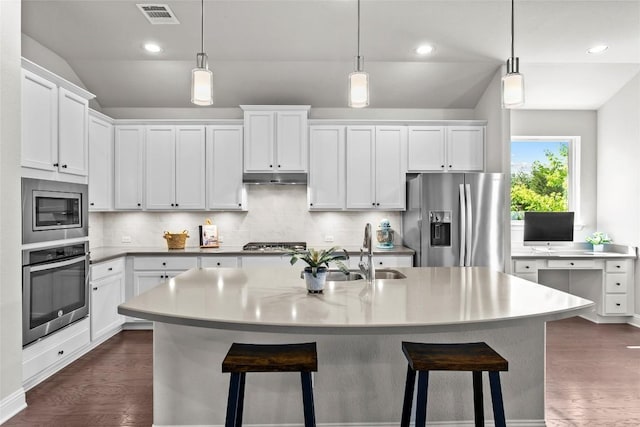 226 Brentwood Dr, Austin, TX 78737 - kitchen featuring stainless steel appliances, lofted ceiling, under cabinet range hood, backsplash, and a kitchen breakfast bar