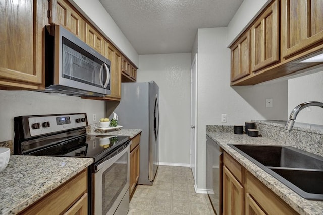 1202 Thorpe Ln Unit 708, San Marcos, TX 78666 - kitchen with stainless steel appliances, a textured ceiling, brown cabinets, and light stone counters