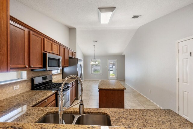 1704 Big Bend Dr, Cedar Park, TX 78613 - kitchen with stainless steel appliances, tasteful backsplash, vaulted ceiling, brown cabinets, and a kitchen island