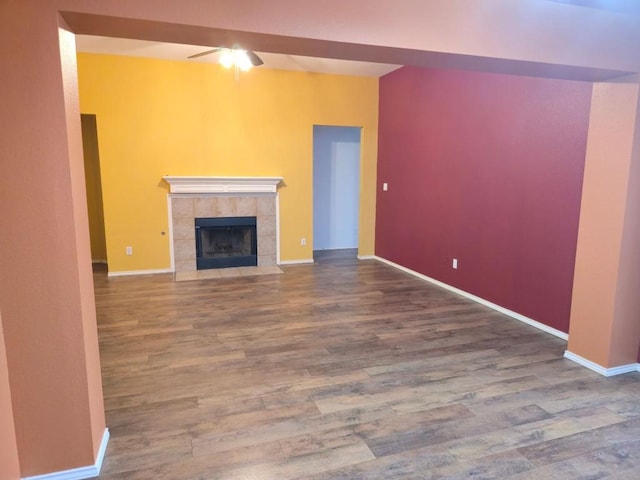 211 Valley Run Trl, Elgin, TX 78621 - unfurnished living room with wood finished floors, a tiled fireplace, and ceiling fan