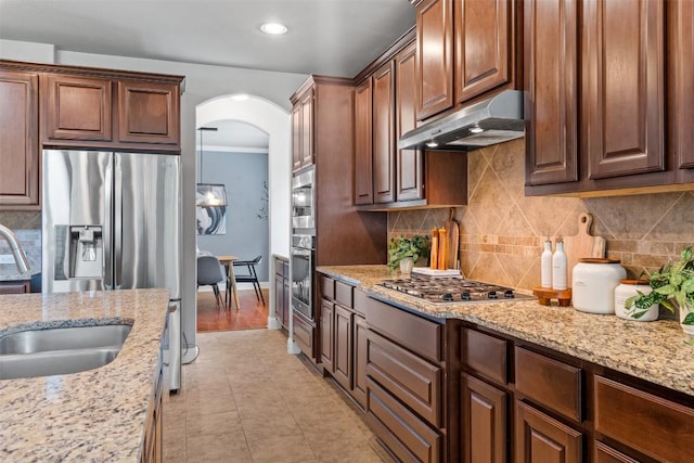 3041 Agave Loop, Round Rock, TX 78681 - kitchen with stainless steel appliances, under cabinet range hood, arched walkways, decorative backsplash, and light stone countertops