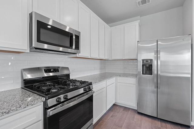 2800 Joe Dimaggio Blvd Unit 84, Round Rock, TX 78665 - kitchen with appliances with stainless steel finishes, white cabinets, light stone counters, wood finished floors, and tasteful backsplash