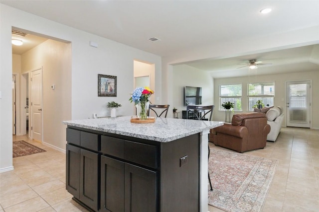 132 Sage Meadows Dr, San Marcos, TX 78666 - kitchen featuring light tile patterned floors, a ceiling fan, a kitchen island, light stone counters, and open floor plan