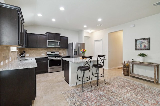 132 Sage Meadows Dr, San Marcos, TX 78666 - kitchen with stainless steel appliances, tasteful backsplash, a kitchen island, a breakfast bar area, and light tile patterned floors
