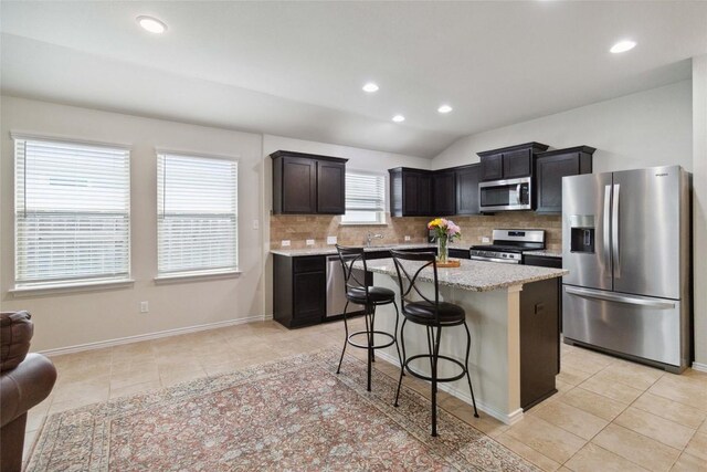 132 Sage Meadows Dr, San Marcos, TX 78666 - kitchen with appliances with stainless steel finishes, tasteful backsplash, light tile patterned floors, recessed lighting, and vaulted ceiling