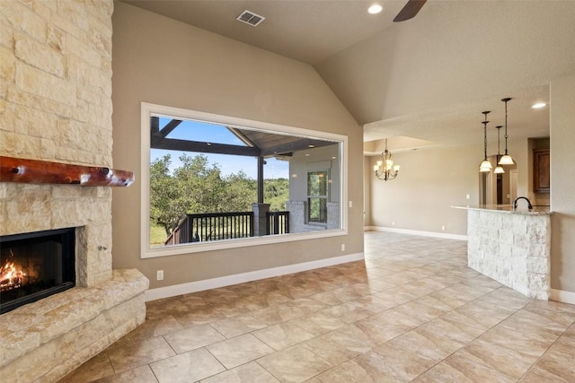 306 Anns Way, Blanco, TX 78606 - unfurnished living room with an outdoor stone fireplace, lofted ceiling, a ceiling fan, a chandelier, and light tile patterned floors