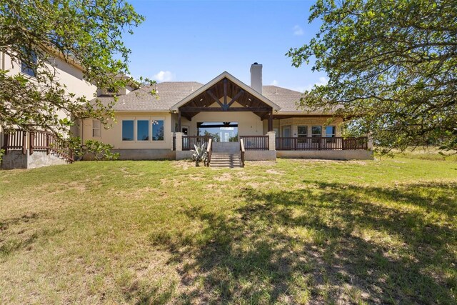 306 Anns Way, Blanco, TX 78606 - back of house featuring a lawn, stucco siding, a chimney, and covered porch