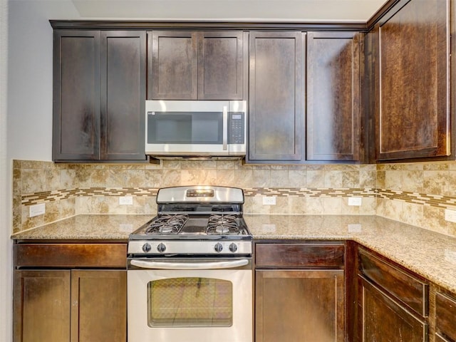 11600 Yeadon Way, Austin, TX 78717 - kitchen featuring appliances with stainless steel finishes, tasteful backsplash, dark brown cabinetry, and light stone countertops