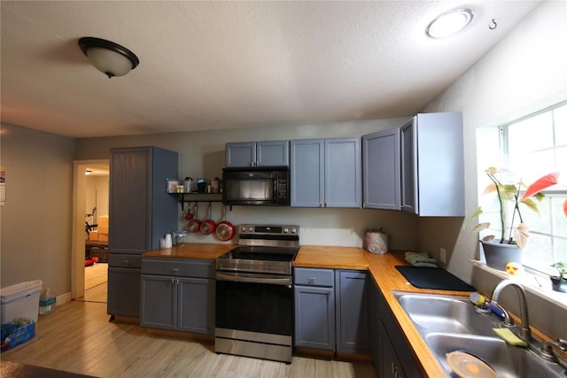 10801 W Lakeview Dr, Jonestown, TX 78645 - kitchen featuring black microwave, stainless steel range with electric cooktop, wooden counters, and plenty of natural light