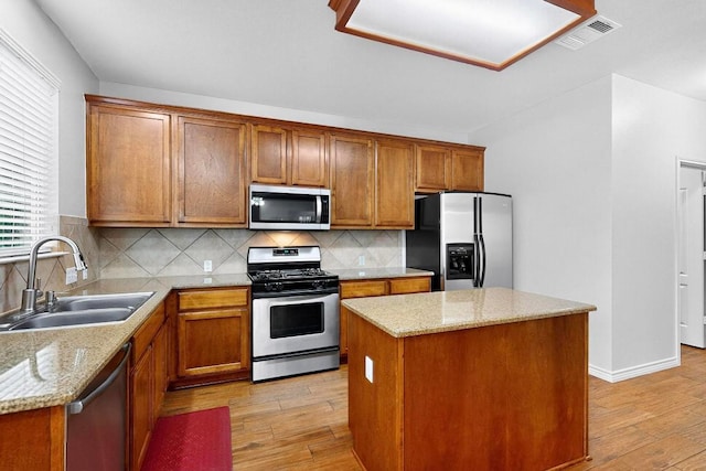 1532 Homewood Cir, Round Rock, TX 78665 - kitchen featuring stainless steel appliances, light wood-style floors, a kitchen island, and brown cabinets