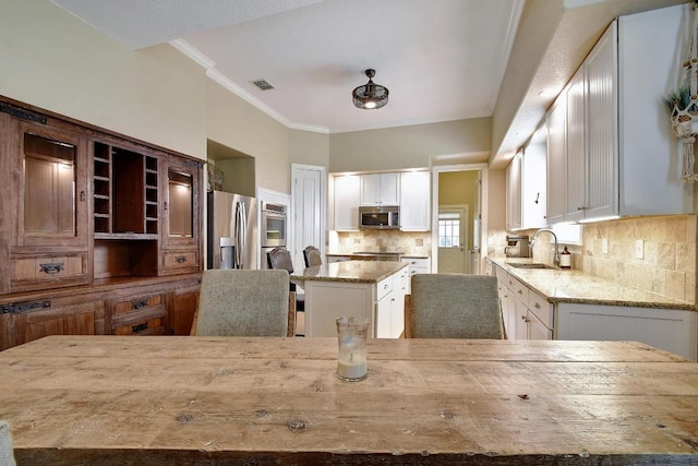 260 N Santa Clara Ave, New Braunfels, TX 78130 - kitchen with stainless steel appliances, light stone countertops, white cabinets, a center island, and crown molding