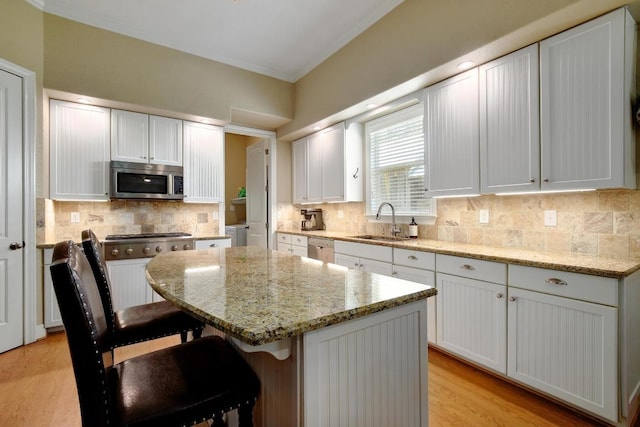 260 N Santa Clara Ave, New Braunfels, TX 78130 - kitchen featuring appliances with stainless steel finishes, a center island, crown molding, tasteful backsplash, and white cabinetry