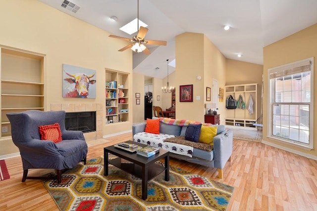 3200 Duval St Unit 309, Austin, TX 78705 - living area featuring light wood-style flooring, built in shelves, a chandelier, a ceiling fan, and a tile fireplace