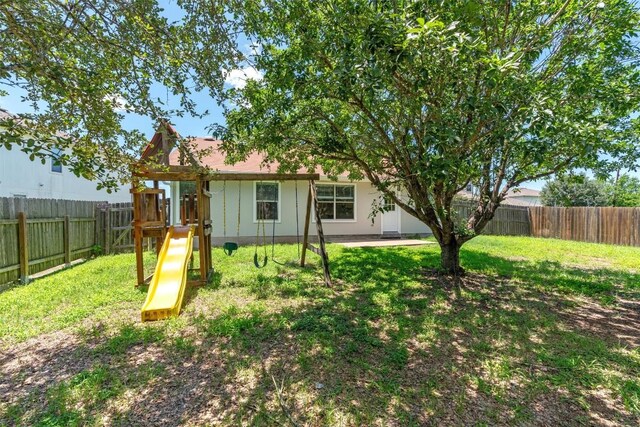 620 Lavaca Loop, Elgin, TX 78621 - rear view of house with a playground and a fenced backyard