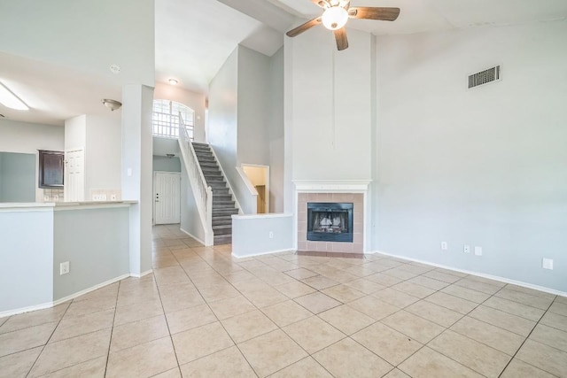 1001 Acanthus St, Pflugerville, TX 78660 - unfurnished living room with high vaulted ceiling, light tile patterned flooring, a ceiling fan, stairs, and a fireplace