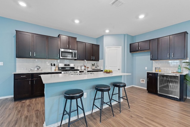 1207 Diggy Dr, Austin, TX 78748 - kitchen featuring stainless steel appliances, beverage cooler, light wood finished floors, tasteful backsplash, and recessed lighting