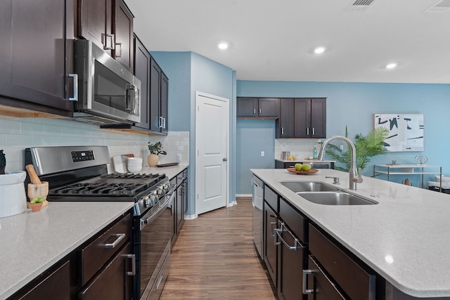 1207 Diggy Dr, Austin, TX 78748 - kitchen featuring appliances with stainless steel finishes, dark wood finished floors, a center island with sink, backsplash, and recessed lighting