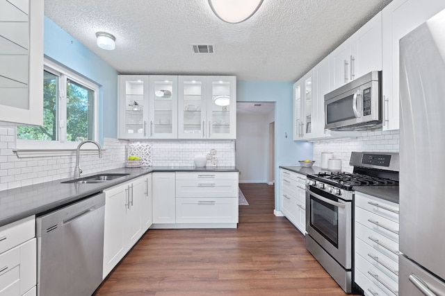 8206 Avocet Dr, Austin, TX 78745 - kitchen with stainless steel appliances, dark countertops, backsplash, a textured ceiling, and dark wood-style flooring