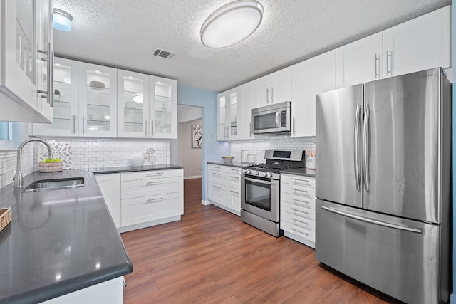 8206 Avocet Dr, Austin, TX 78745 - kitchen with stainless steel appliances, dark countertops, white cabinets, dark wood-style floors, and a textured ceiling
