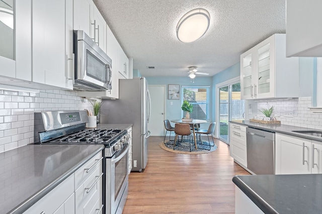 8206 Avocet Dr, Austin, TX 78745 - kitchen featuring appliances with stainless steel finishes, a ceiling fan, light wood finished floors, dark countertops, and white cabinetry
