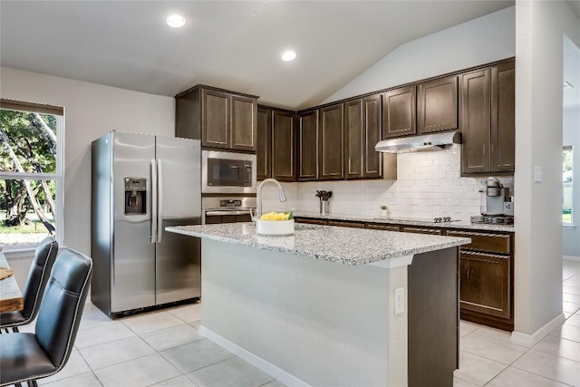 1901 Owens Ln, Lago Vista, TX 78645 - kitchen featuring stainless steel appliances, under cabinet range hood, dark brown cabinetry, vaulted ceiling, and light stone counters