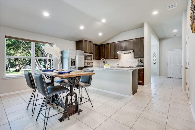 1901 Owens Ln, Lago Vista, TX 78645 - kitchen with appliances with stainless steel finishes, dark brown cabinetry, decorative backsplash, lofted ceiling, and under cabinet range hood