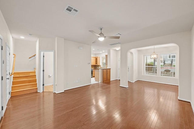 1900 Tramson Dr Unit 94C, Austin, TX 78741 - unfurnished living room with a ceiling fan, wood finished floors, arched walkways, and stairs