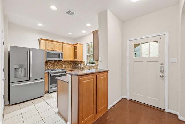 1900 Tramson Dr Unit 94C, Austin, TX 78741 - kitchen featuring appliances with stainless steel finishes, a peninsula, decorative backsplash, glass insert cabinets, and recessed lighting