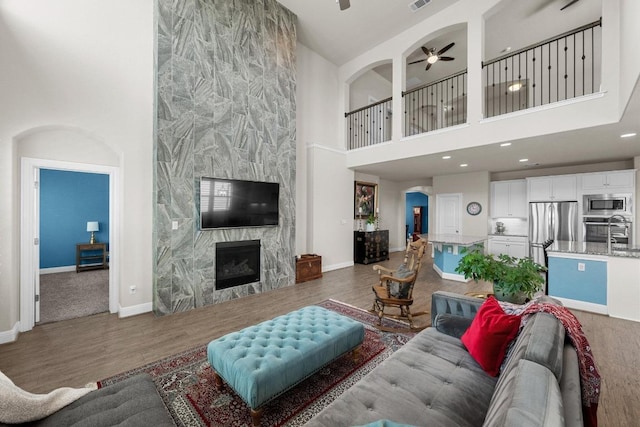 15913 Villa Frontera Dr, Bee Cave, TX 78738 - living area with a towering ceiling, a ceiling fan, a premium fireplace, wood finished floors, and recessed lighting