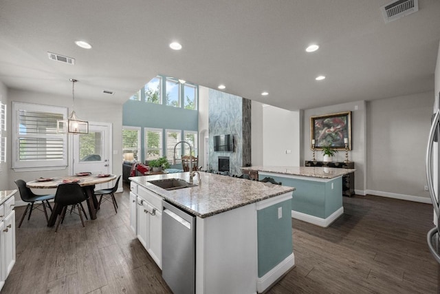 15913 Villa Frontera Dr, Bee Cave, TX 78738 - kitchen with a center island with sink, stainless steel dishwasher, a large fireplace, dark wood-style flooring, and recessed lighting