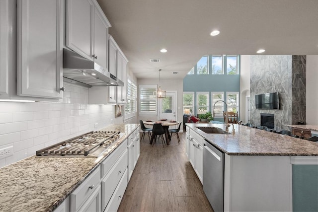 15913 Villa Frontera Dr, Bee Cave, TX 78738 - kitchen featuring stainless steel appliances, under cabinet range hood, a large fireplace, recessed lighting, and decorative backsplash