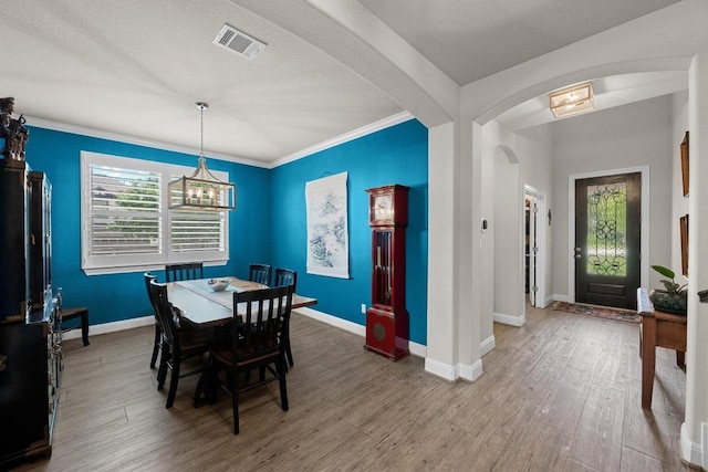 15913 Villa Frontera Dr, Bee Cave, TX 78738 - dining area featuring wood finished floors, arched walkways, ornamental molding, and a chandelier