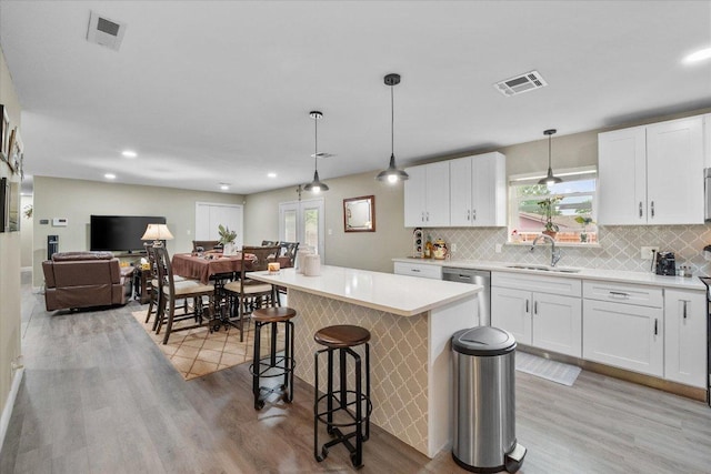 1410 Hummingbird Dr, Hillsboro, TX 76645 - kitchen with stainless steel dishwasher, light wood-style flooring, a breakfast bar, tasteful backsplash, and recessed lighting