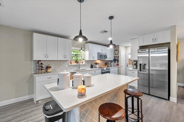 1410 Hummingbird Dr, Hillsboro, TX 76645 - kitchen featuring stainless steel appliances, light wood-type flooring, backsplash, and white cabinetry