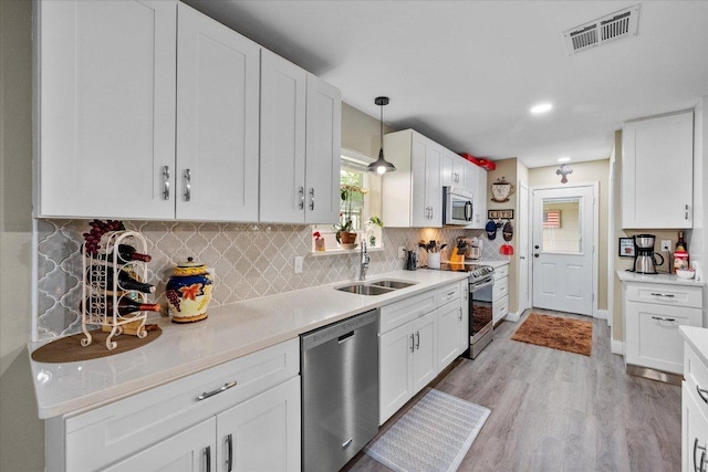 1410 Hummingbird Dr, Hillsboro, TX 76645 - kitchen with appliances with stainless steel finishes, white cabinets, light wood finished floors, light countertops, and backsplash