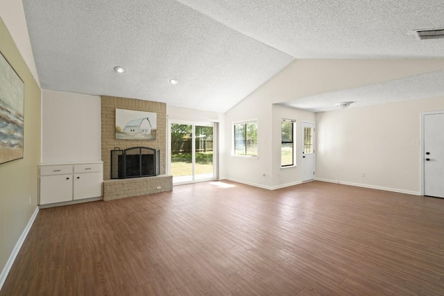 132 Spanish Oak Dr, Georgetown, TX 78628 - unfurnished living room with a textured ceiling, lofted ceiling, wood finished floors, and a fireplace